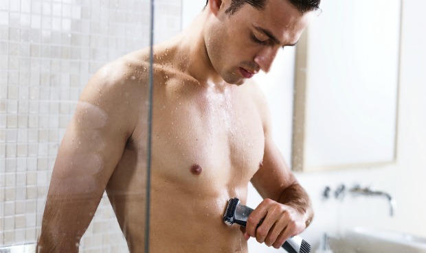 hombre utilizando depiladora eléctrica en la ducha 
