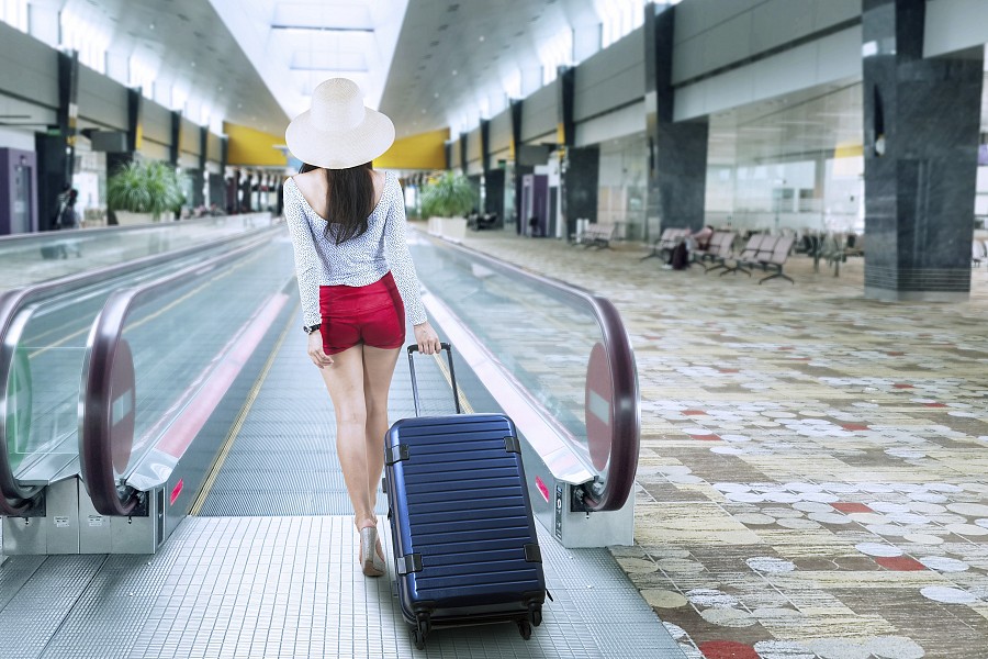 mujer viajando con una maleta de plástico duro