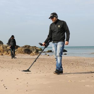 hombre usando detector de metales en la playa