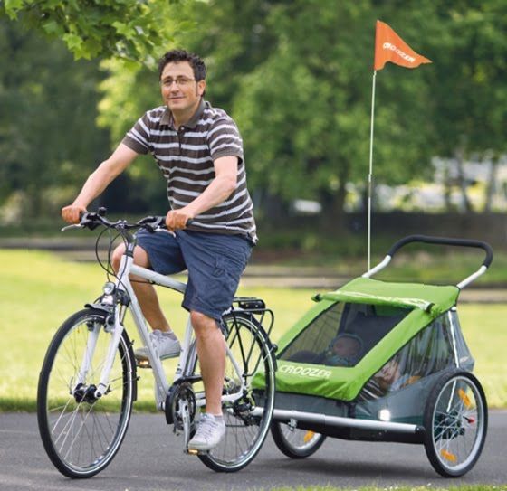 padre paseando en bicicleta con un remolque para bebés