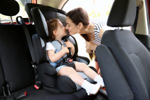 mujer colocando a su hija en la silla del coche 